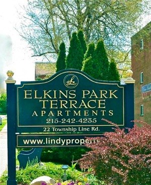 Building entrance with sign, statue, and flowers.